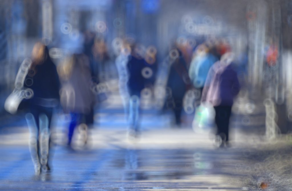 A blurred group of people walking on a sidewalk