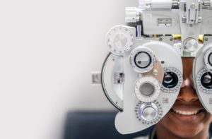 A person at their optometrist getting examined with a phoropter to measure any refractive efforts and their eyeglasses prescription