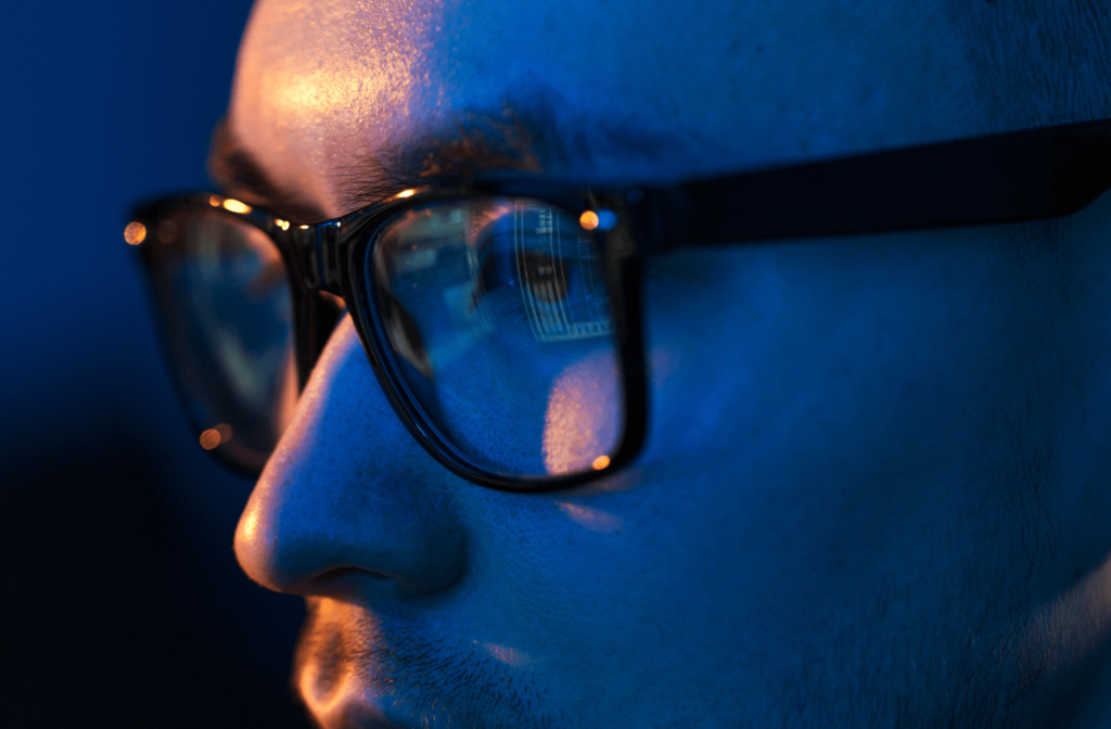 A man wearing glasses with blue light protection while he uses his computer