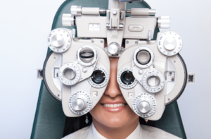 A woman sits behind a phoropter at the optometrist's office. A phoropter is a tool used to determine refractive errors