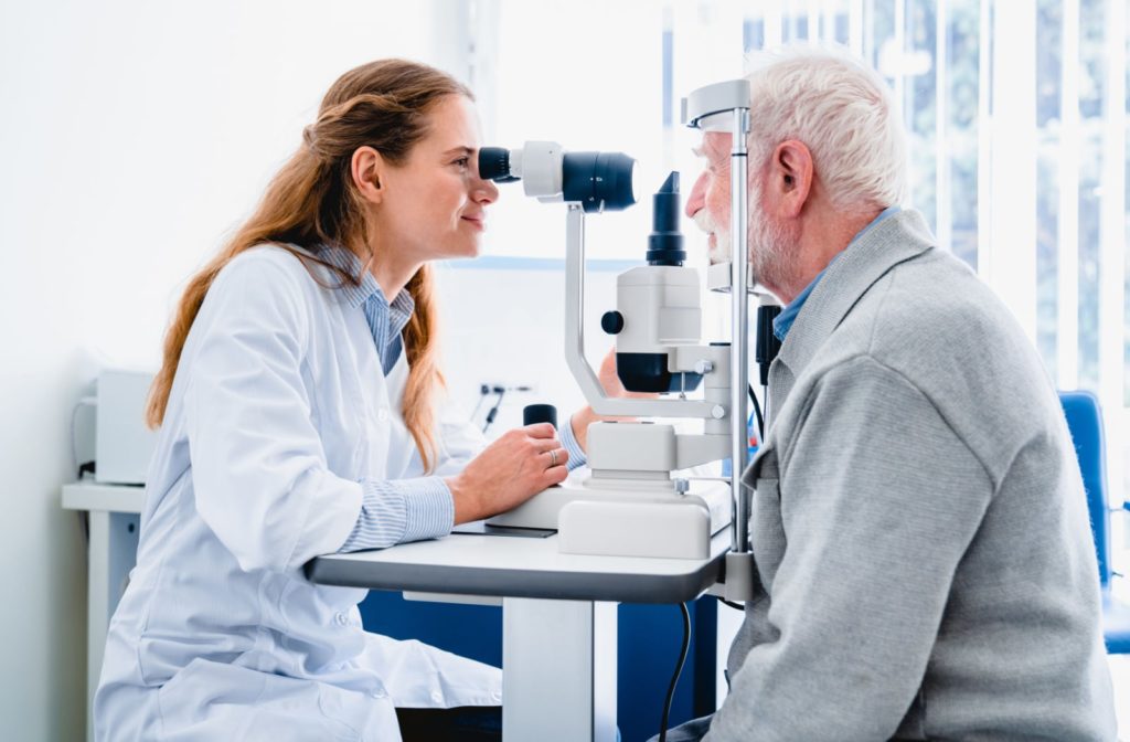 A female optometrist examines an older patient's eyes to detect any signs of eye diseases or other health issues.