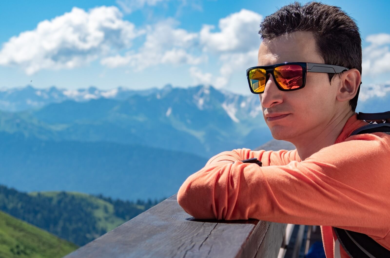 A man wearing mirrored, polarized sunglasses outside on a sunny day.