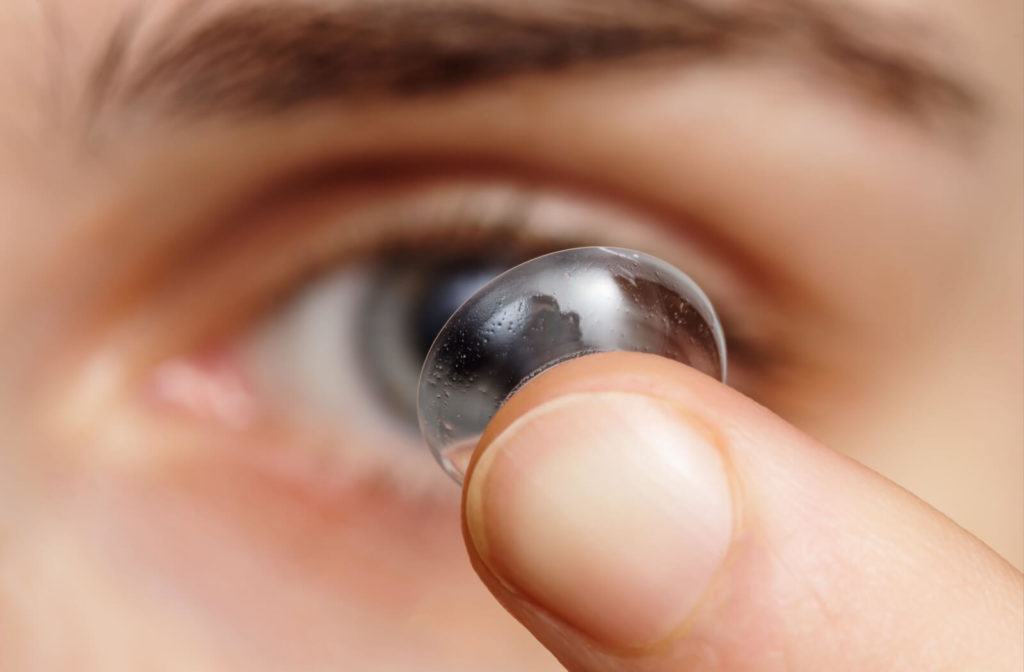 Close-up of a contact lens being held near an eye for application.