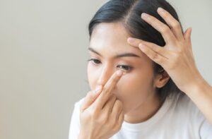 An image of an adult placing a contact lens in their eye.