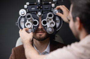 An optometrist adjusts the phoropter during a patient's routine eye exam.